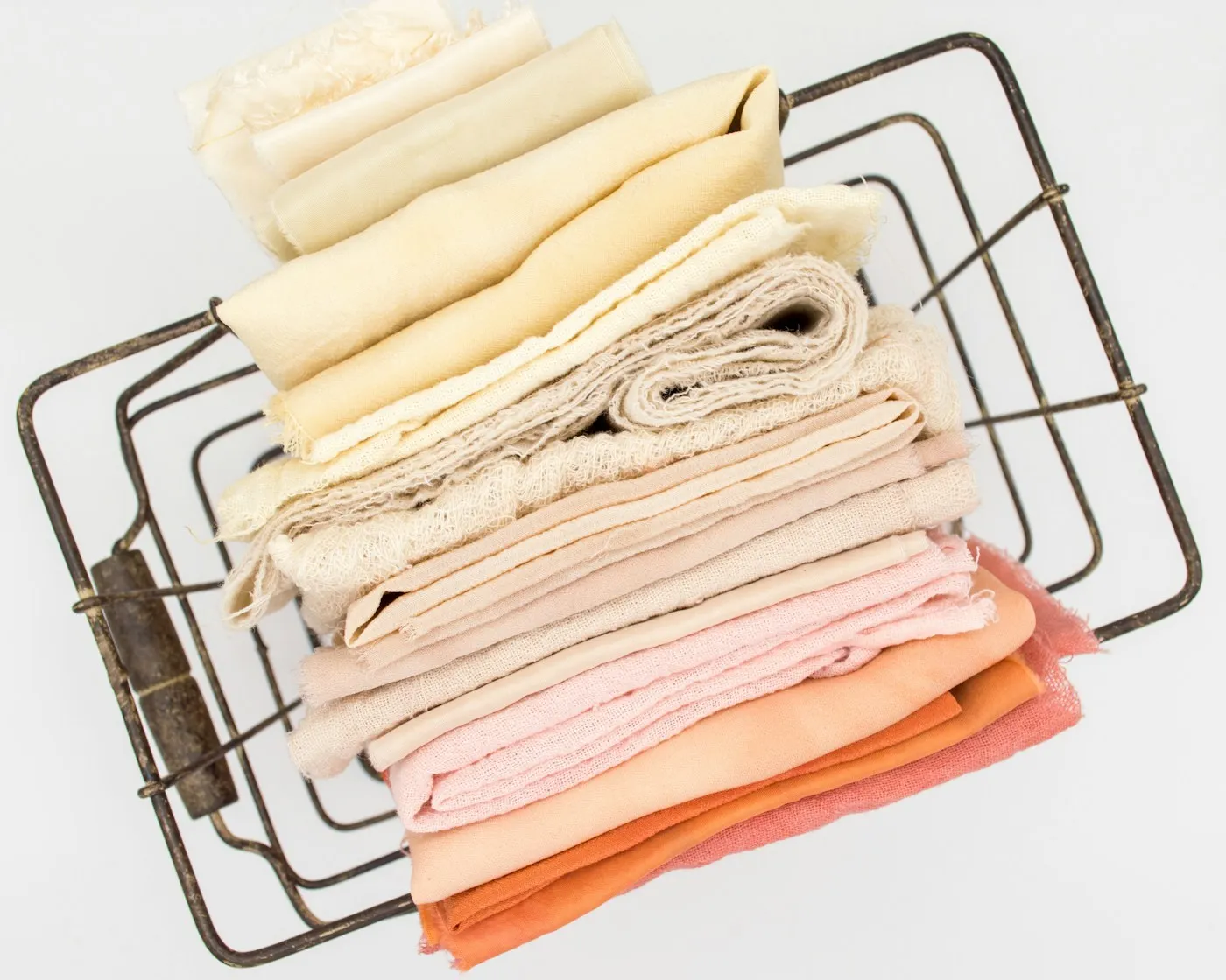 A wire basket of folded fabric in warm neutrals